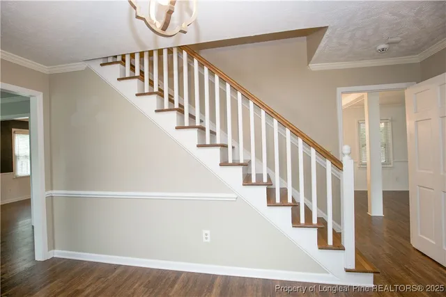 a view of staircase with lots of frames on wall and wooden floor