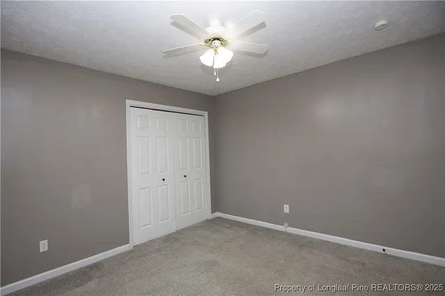 an empty room with a chandelier fan and a ceiling fan