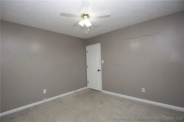 an empty room with a chandelier fan and windows