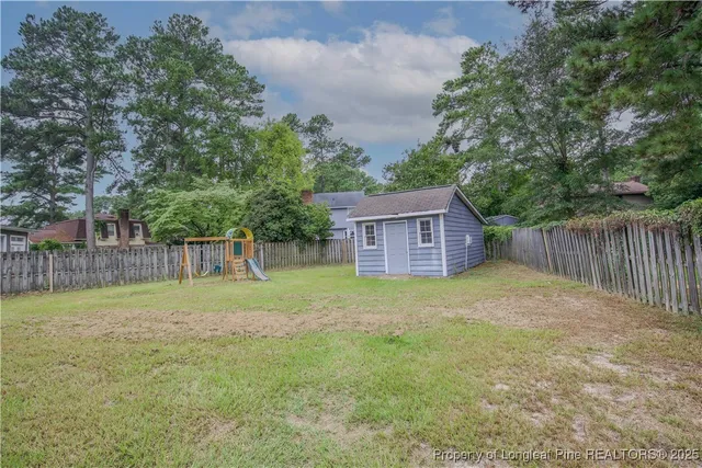 a backyard of a house with trees and wooden fence
