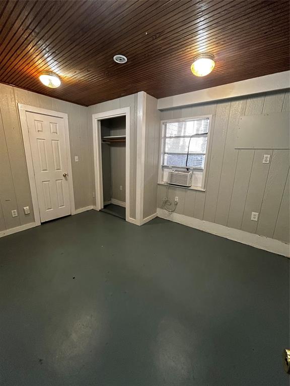 903 West 30th Street, Unit B Austin, TX 78705 - Photo 7 of 9 Unfurnished bedroom featuring concrete floors, wood walls, and a closet,.