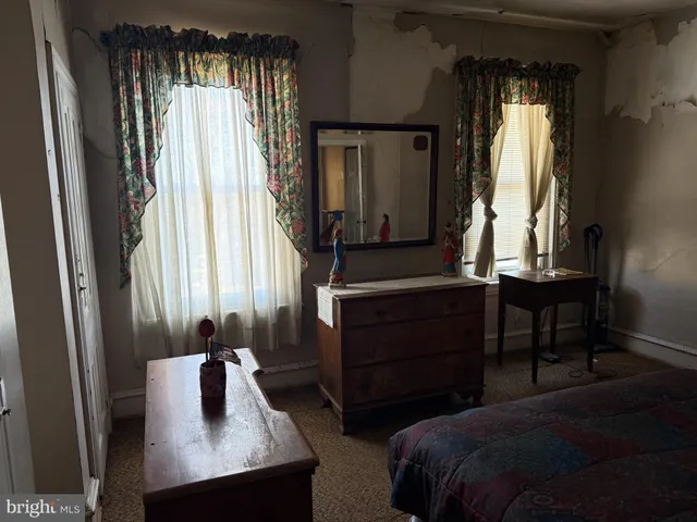 a bedroom with a bed and a dresser next to a window