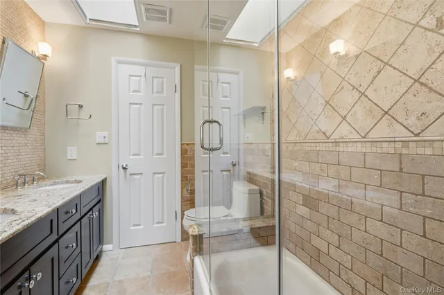 a bathroom with a granite countertop sink a mirror and shower