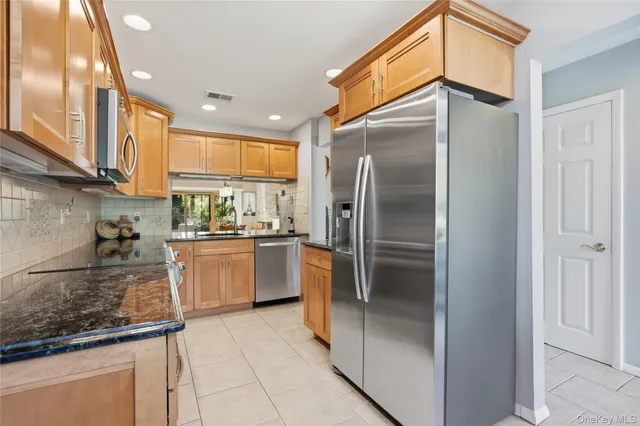 a kitchen with stainless steel appliances granite countertop a refrigerator a oven and white cabinets
