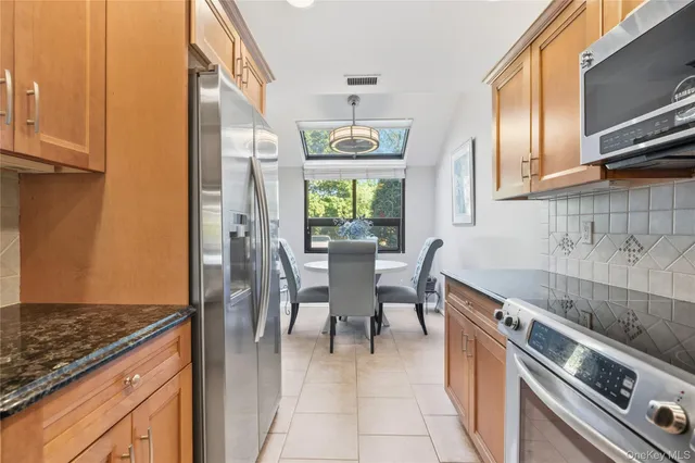 a kitchen with stainless steel appliances granite countertop a stove top oven a sink dishwasher a dining table and chairs with wooden floor