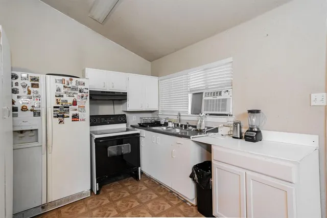 a kitchen with refrigerator a stove a sink and white cabinets with wooden floor