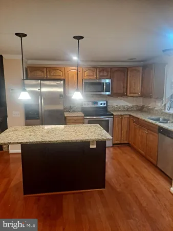 a kitchen with kitchen island granite countertop a sink a counter top space and stainless steel appliances