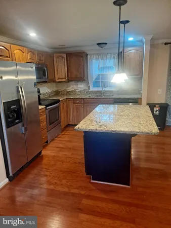 a kitchen with stainless steel appliances granite countertop a sink a stove and a wooden floors