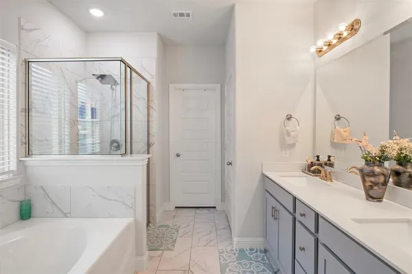 a bathroom with a double vanity sink mirror and bathtub