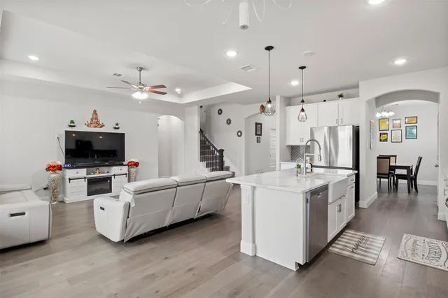 a large white kitchen with a large island oven a stove a dining table and chairs