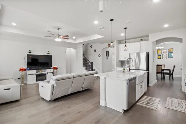 a large white kitchen with a large island oven a stove a dining table and chairs