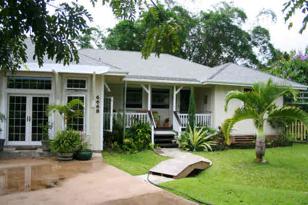 a view of a house with backyard garden and a tree