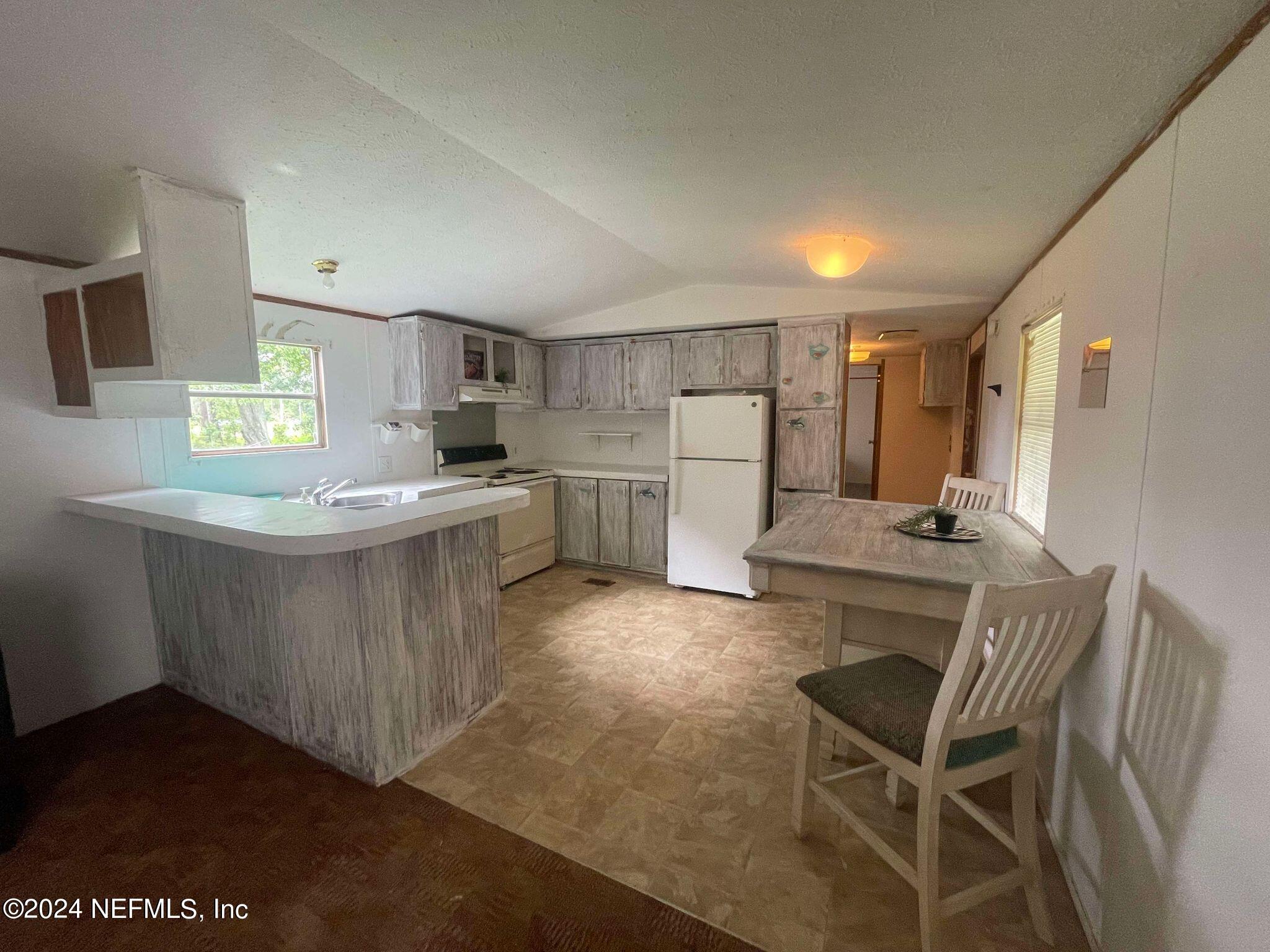 12550 Southeast 55th Place Starke, FL 32091 - Photo 3 of 29 a kitchen with a table chairs refrigerator and microwave