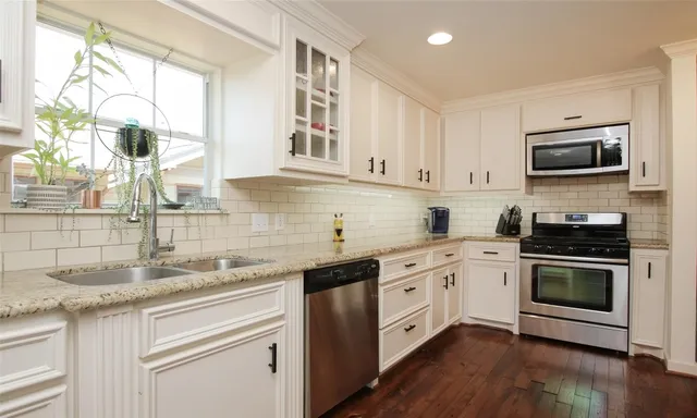 a kitchen with granite countertop white cabinets and appliances