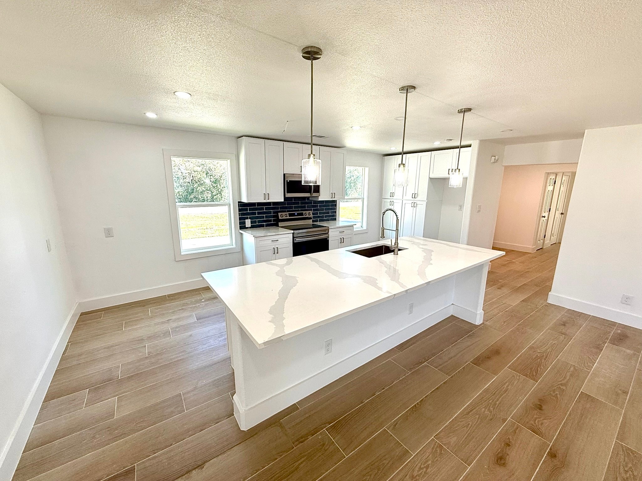 1214 Main Street Alvin, TX 77511 - Photo 7 of 18 This spacious, bright kitchen features wood-style flooring, recessed lighting, and large windows allowing natural light to fill the room.