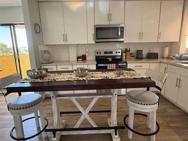 a kitchen with a stove a table and chairs in it
