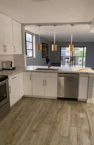 a kitchen with kitchen island granite countertop a stove a sink and white cabinets
