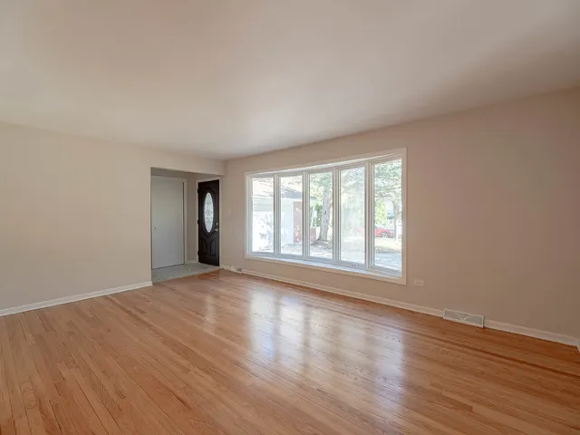 a view of an empty room with wooden floor and window
