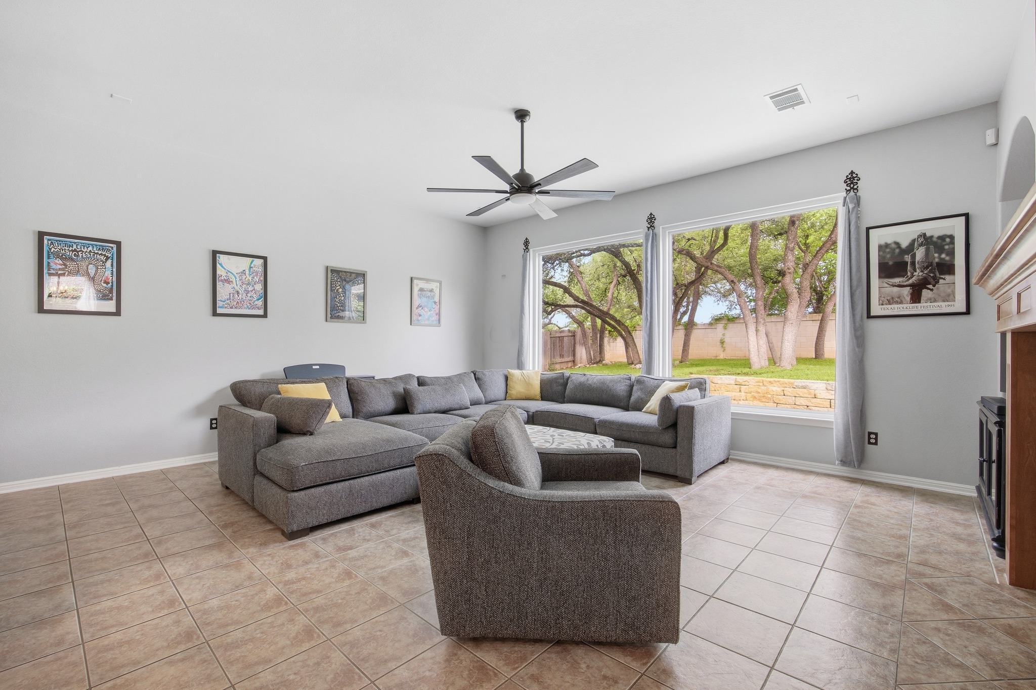 2204 Rio Mesa Drive Austin, TX 78732 - Photo 12 of 40 Living area featuring tiled flooring, a ceiling fan, and large windows offering views of the exterior landscape with mature trees