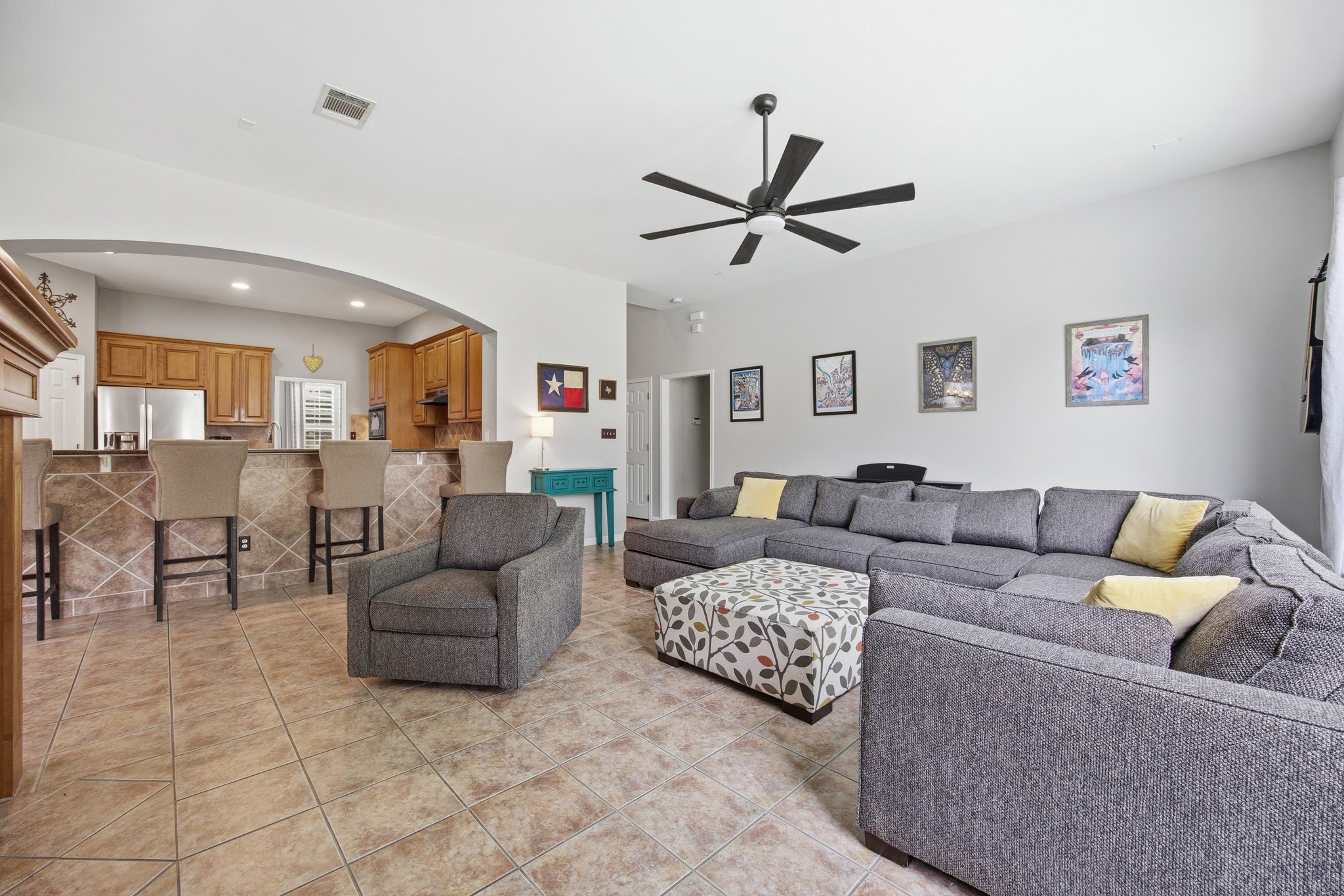 2204 Rio Mesa Drive Austin, TX 78732 - Photo 13 of 40 Spacious living area featuring tiled flooring, an arched entryway to the kitchen, and a ceiling fan