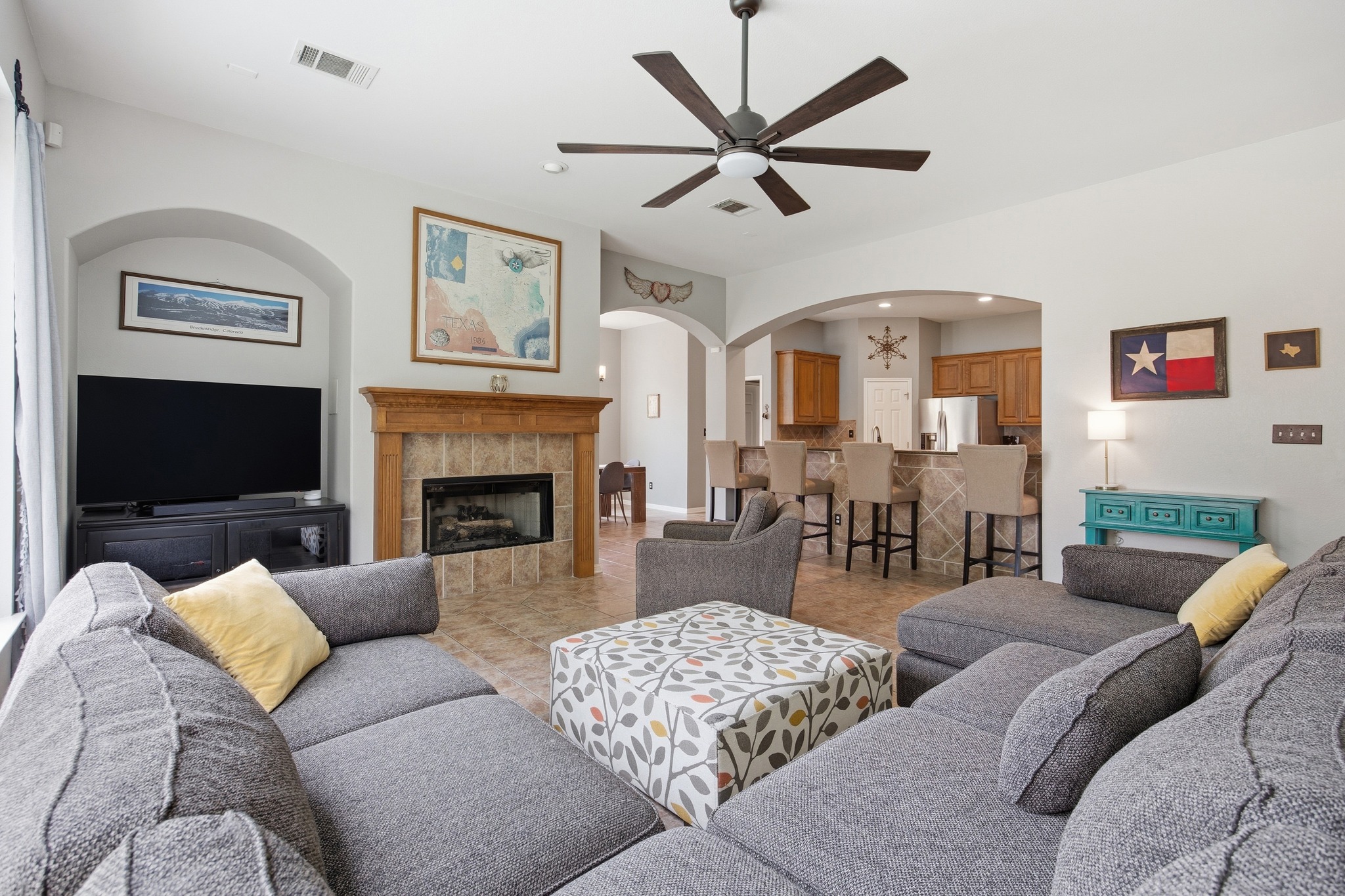 2204 Rio Mesa Drive Austin, TX 78732 - Photo 14 of 40 Living area featuring light gray walls, a ceiling fan, a tiled fireplace with a wooden mantel, and arched doorways