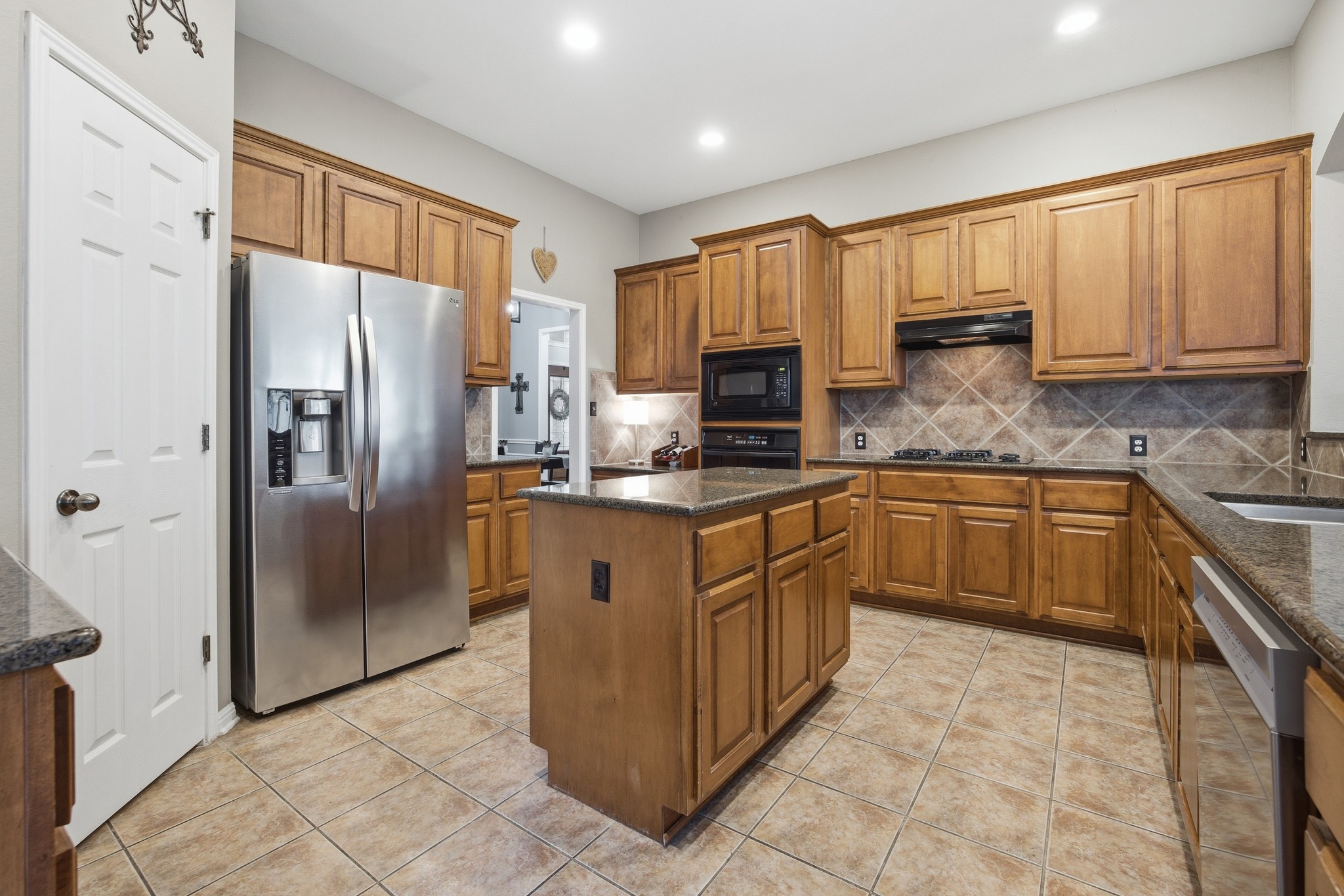2204 Rio Mesa Drive Austin, TX 78732 - Photo 15 of 40 Well-appointed kitchen featuring wood cabinetry, granite countertops, tile flooring, and a stainless steel refrigerator