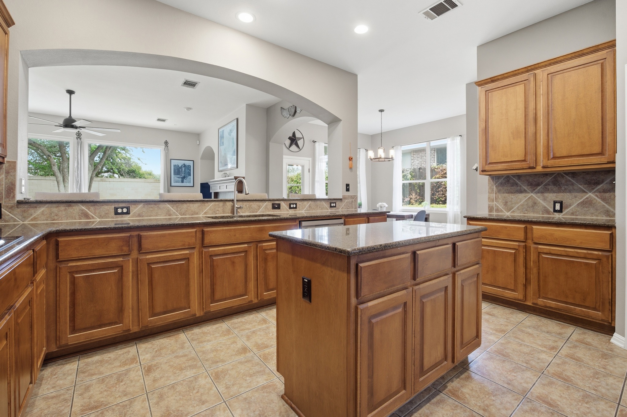 2204 Rio Mesa Drive Austin, TX 78732 - Photo 17 of 40 The kitchen features wood cabinetry, tile flooring, and a central island with a granite countertop