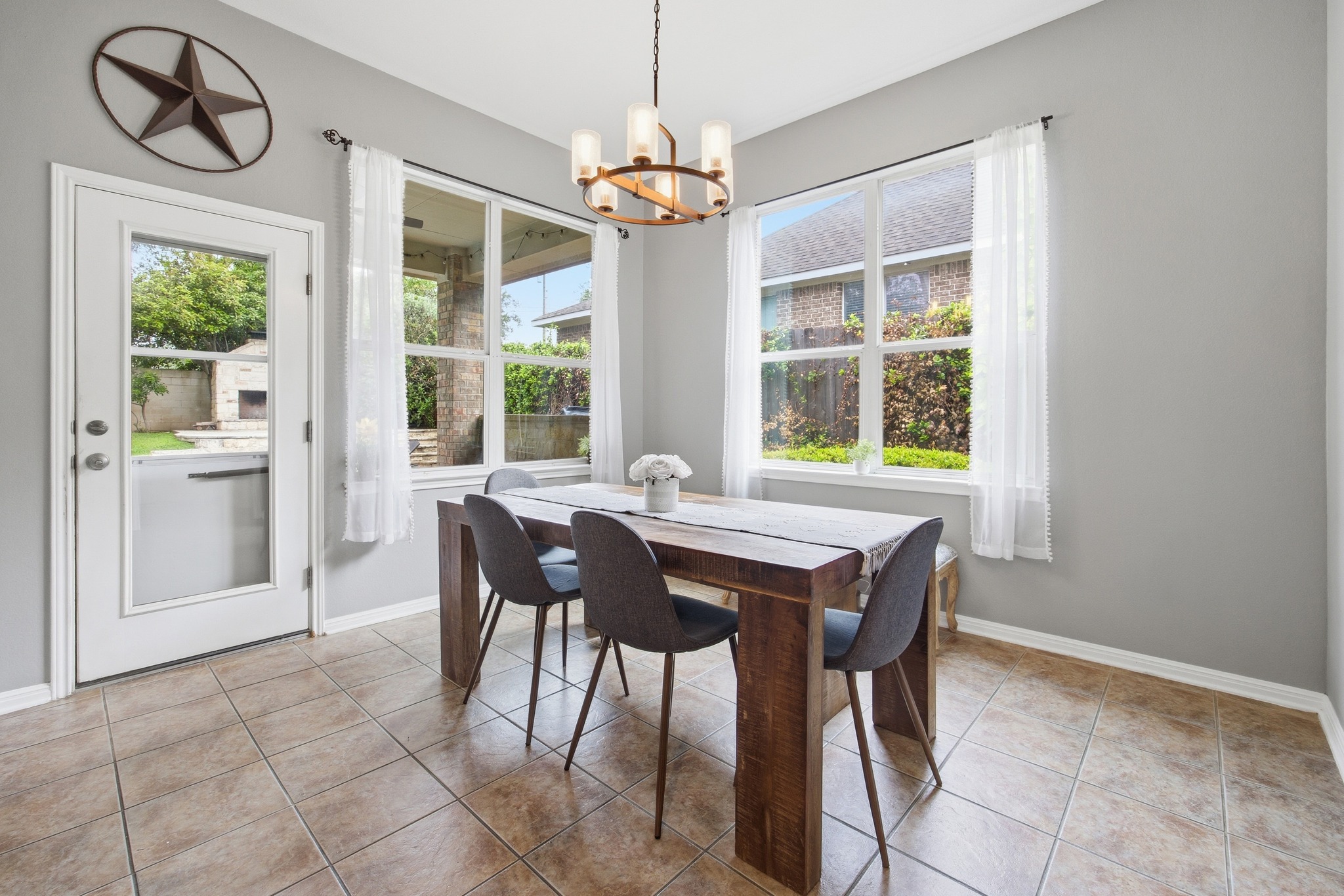 2204 Rio Mesa Drive Austin, TX 78732 - Photo 19 of 40 Dining area featuring tiled flooring, a transom window over a full-light door providing direct access to the yard, and a large window offering views of greenery