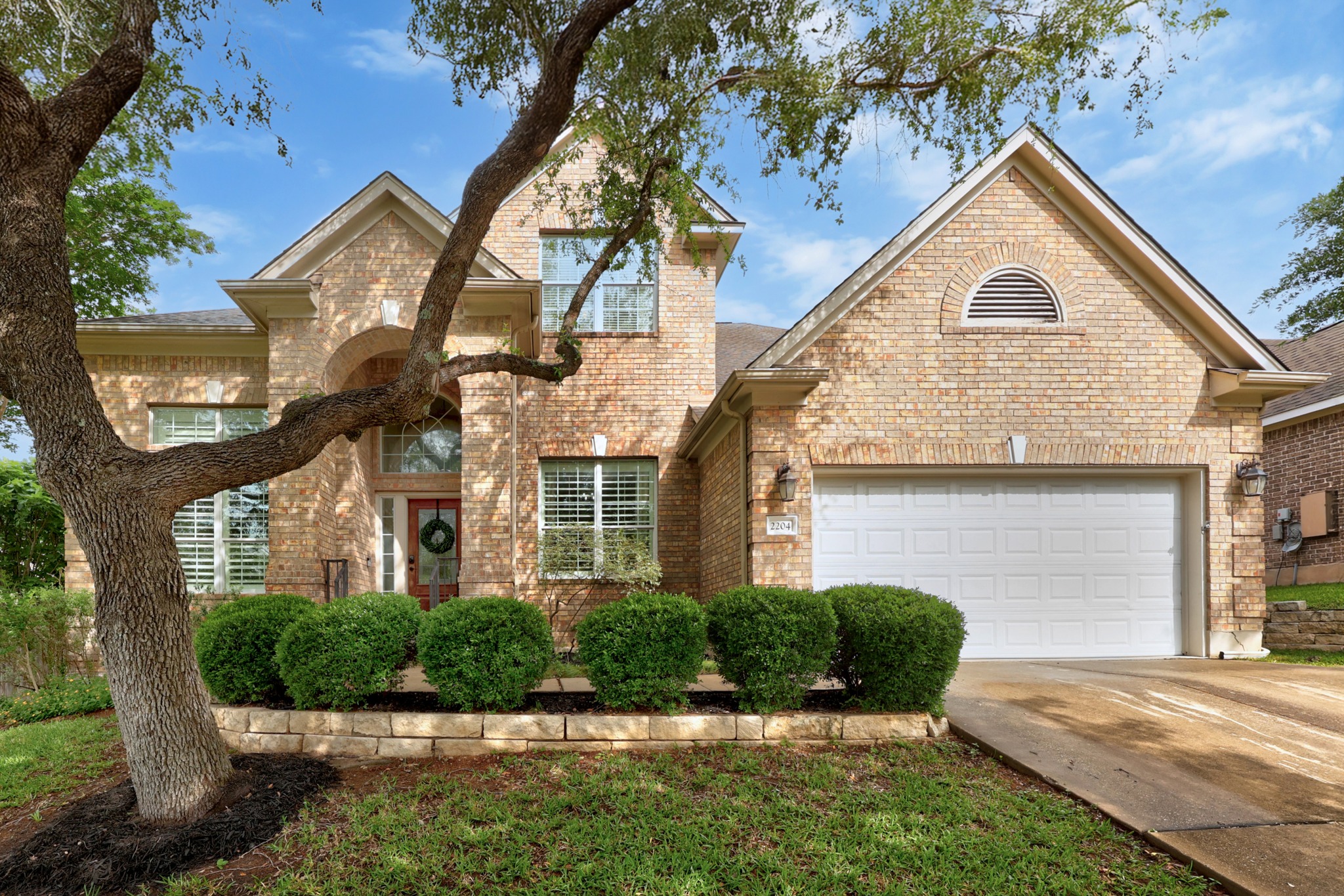 2204 Rio Mesa Drive Austin, TX 78732 - Photo 2 of 40 The property features a brick exterior, an attached garage, and a well-maintained lawn