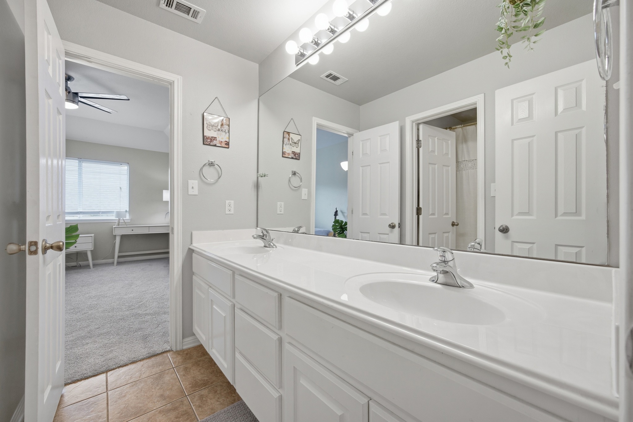 2204 Rio Mesa Drive Austin, TX 78732 - Photo 33 of 40 Bathroom vanity featuring two sinks with chrome faucets, a large mirror, and a light fixture with multiple bulbs