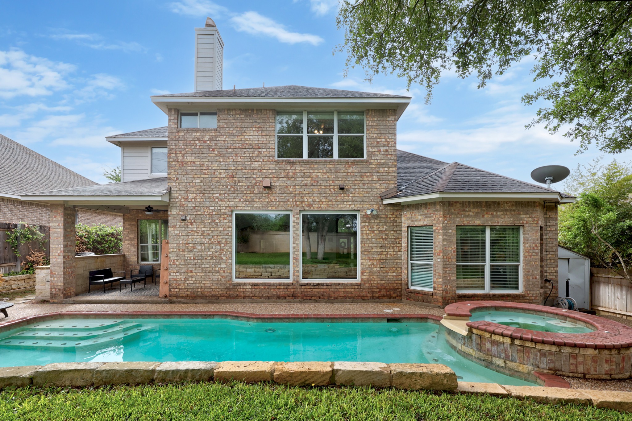 2204 Rio Mesa Drive Austin, TX 78732 - Photo 34 of 40 The property features an exterior of brick construction, a swimming pool with integrated steps, and a separate hot tub
