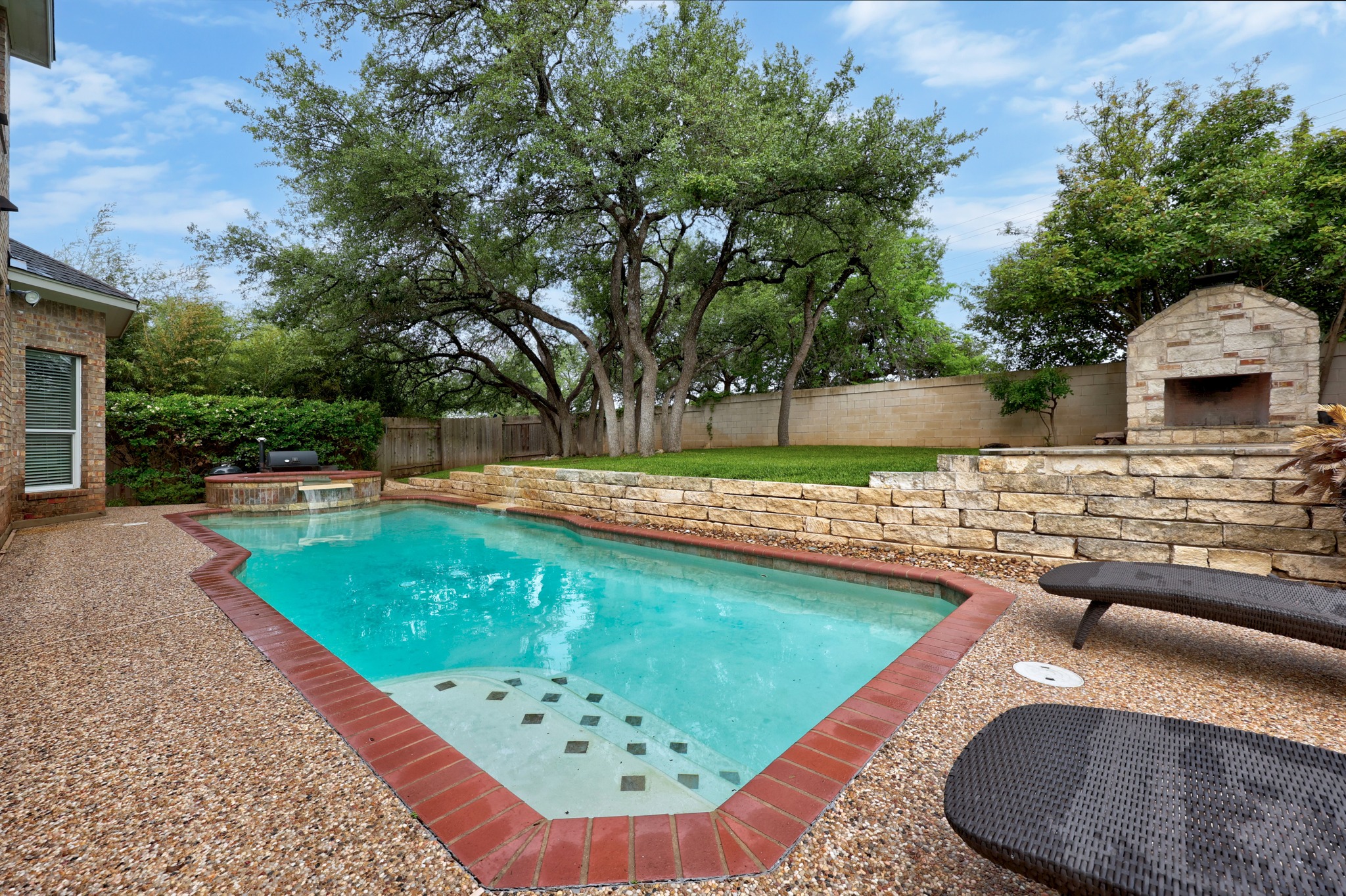 2204 Rio Mesa Drive Austin, TX 78732 - Photo 36 of 40 The property features a swimming pool with brick coping, a stone retaining wall, and an outdoor stone fireplace
