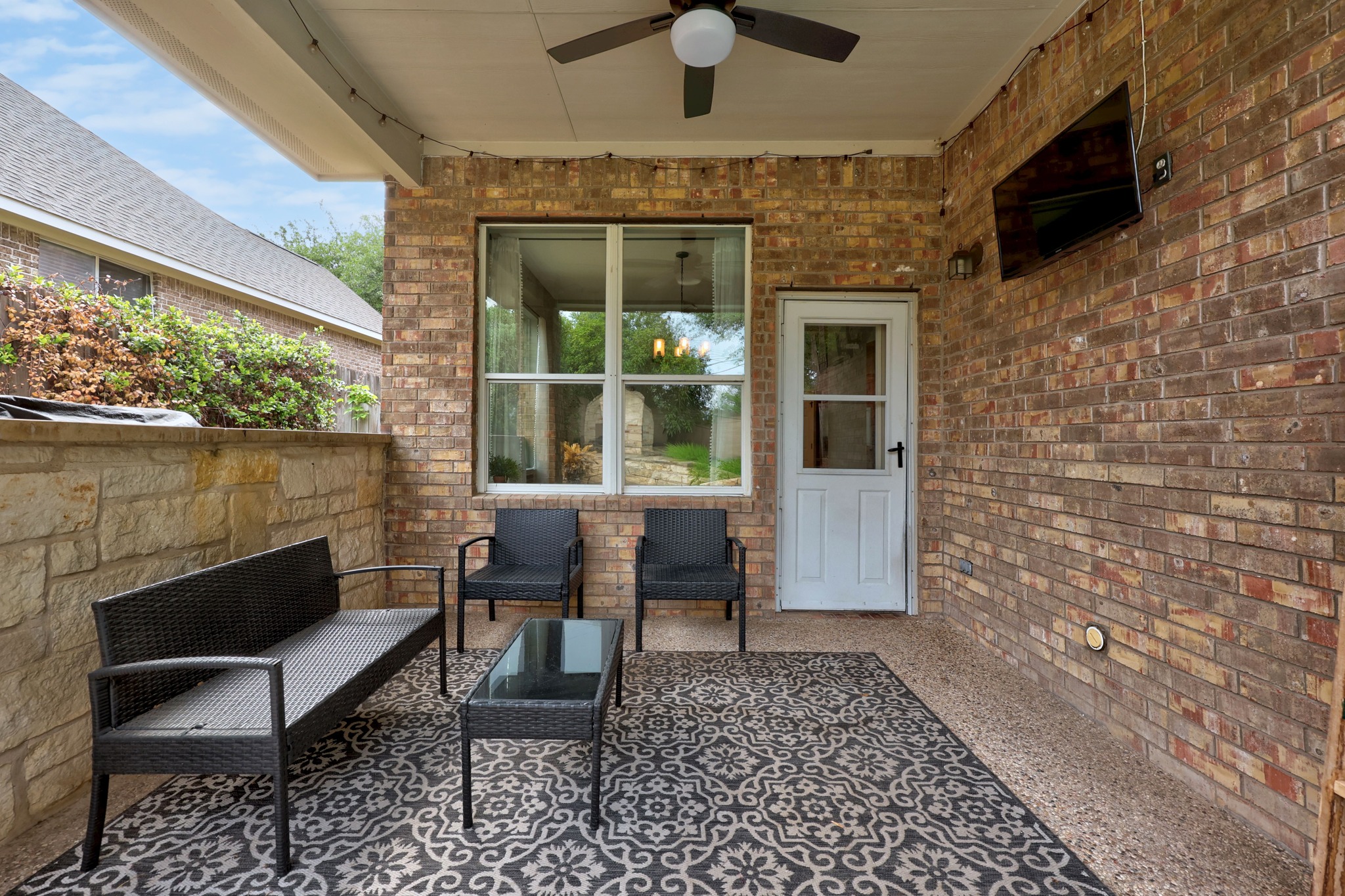 2204 Rio Mesa Drive Austin, TX 78732 - Photo 39 of 40 This property features an inviting covered patio with brick exterior walls, a ceiling fan, and a patterned outdoor rug