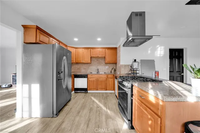 a kitchen with stainless steel appliances granite countertop a refrigerator a stove a sink and a oven