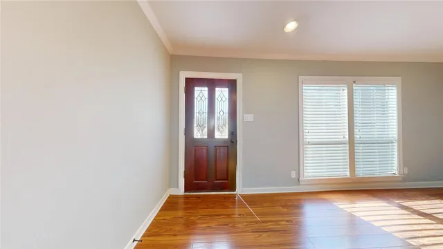 a view of an empty room with window and a kitchen