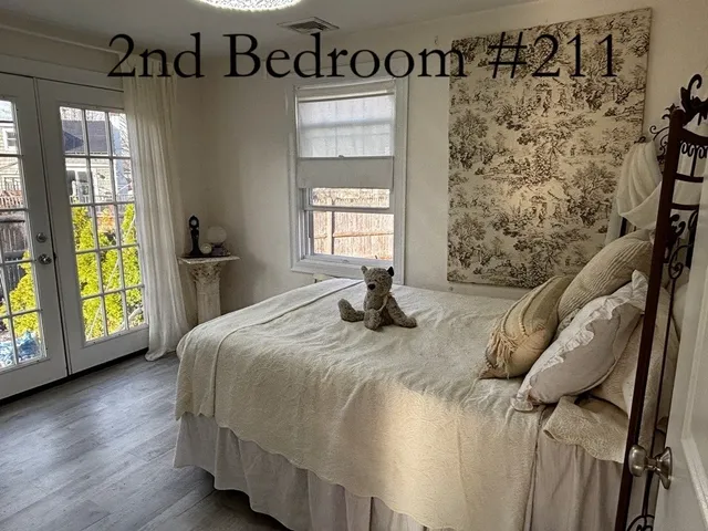 a bedroom with a bed next to a window with wooden floor
