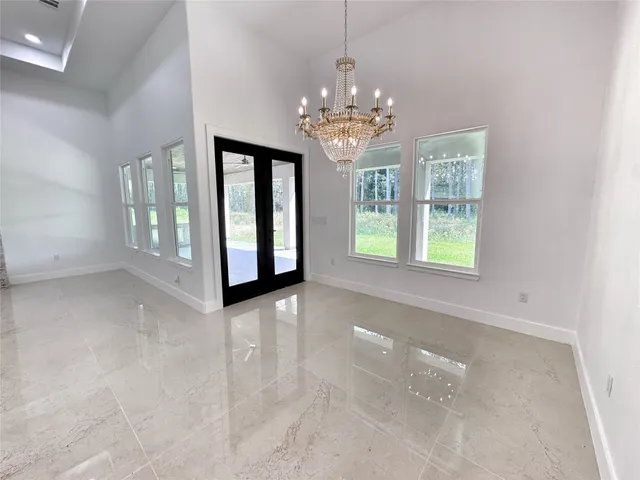 a view of an empty room with window and chandelier