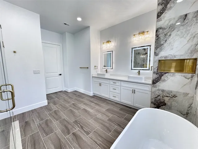 a bathroom with a double vanity sink a mirror and a bathtub
