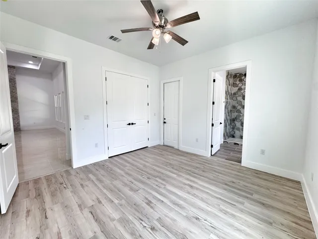 an empty room with wooden floor and a ceiling fan