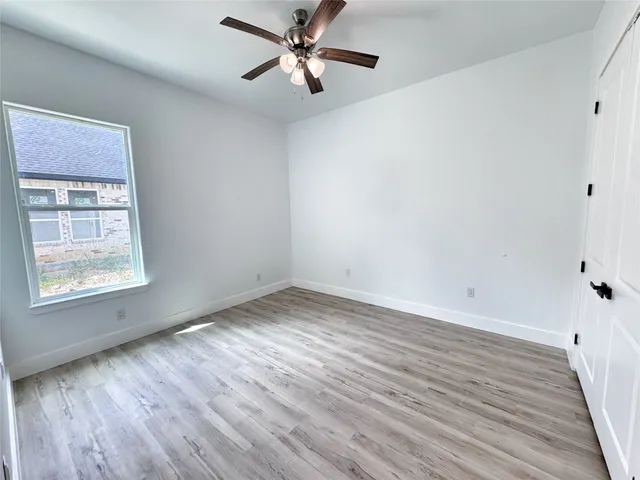 a view of empty room with wooden floor and fan