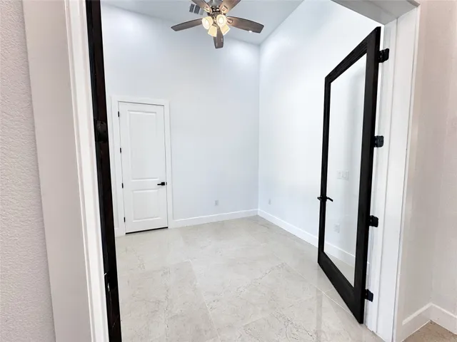 an empty room with windows and fan