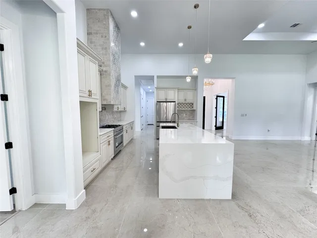 a large kitchen with stainless steel appliances kitchen island a large counter top and a refrigerator