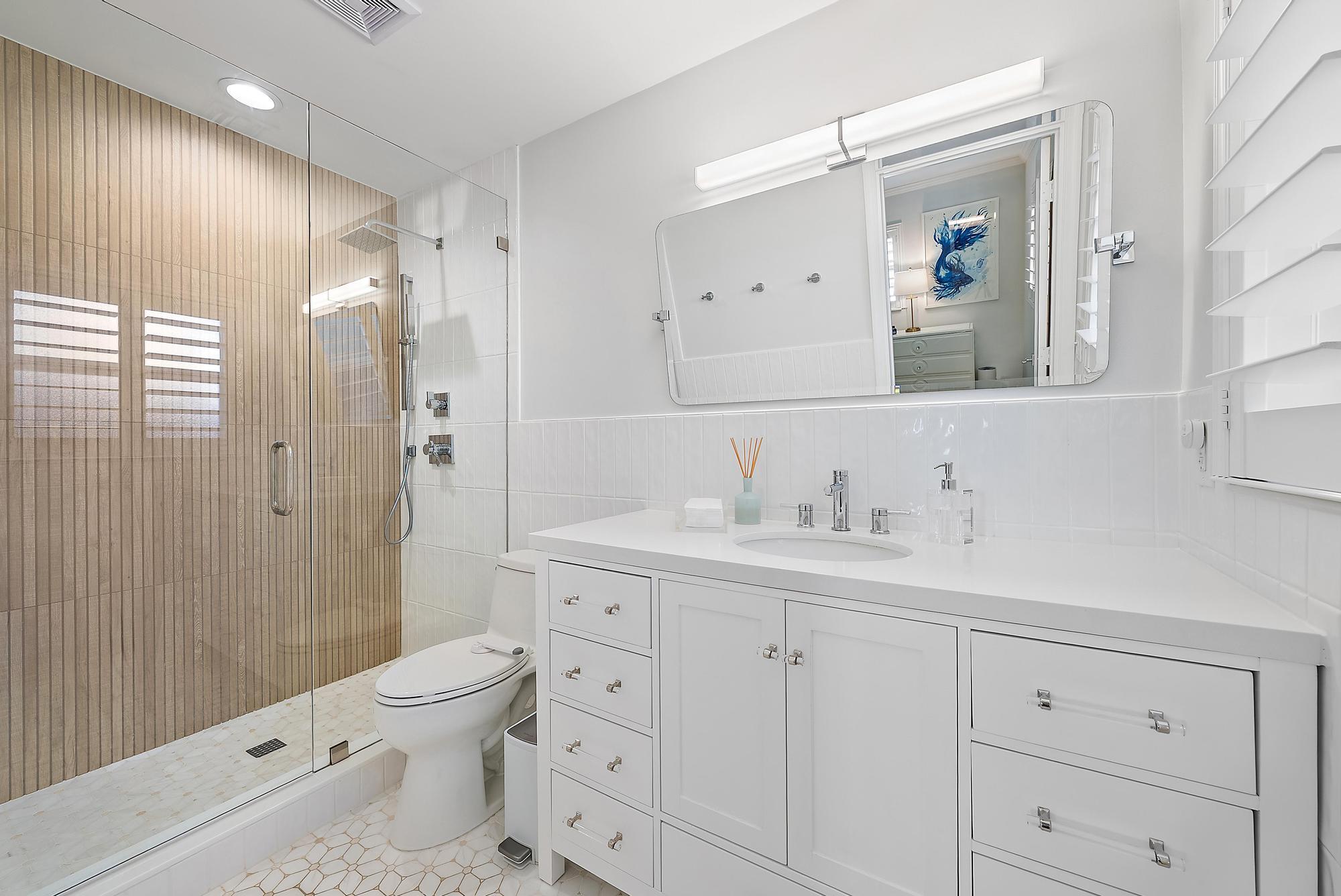 4967 Bimini Road Tequesta, FL 33469 - Photo 25 of 36 a bathroom with a toilet a sink a glass door a shower a and mirror