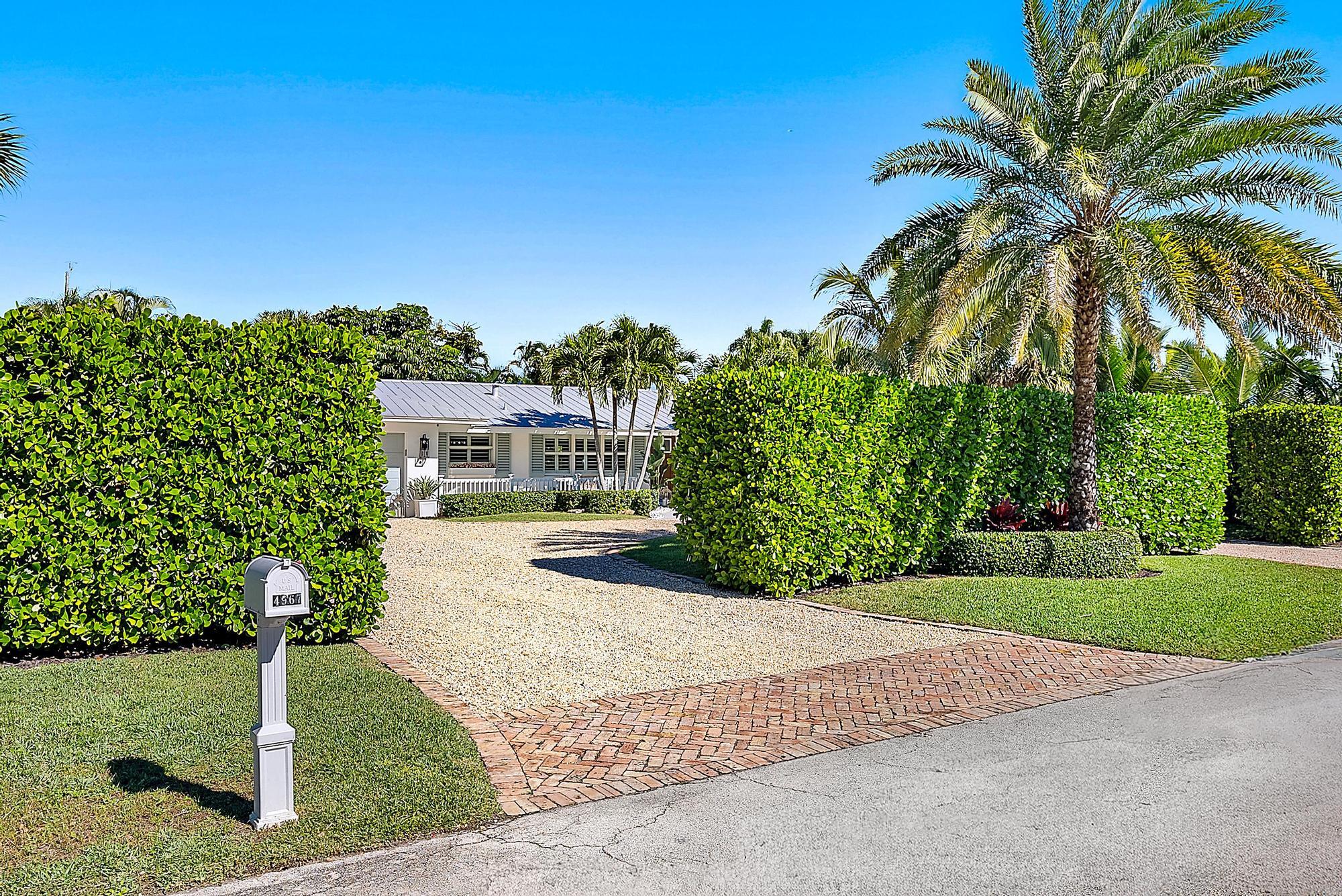 4967 Bimini Road Tequesta, FL 33469 - Photo 4 of 36 a front view of a house with a yard garage and outdoor seating