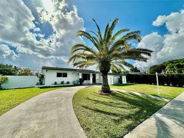 a front view of a house with a big yard and potted plants