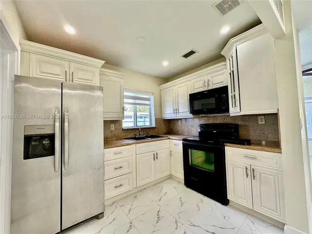 a kitchen with stainless steel appliances granite countertop a refrigerator a sink a stove a microwave and wooden cabinets