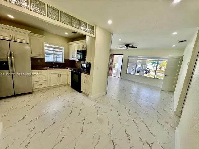 a large white kitchen with a sink and dishwasher a stove top oven with wooden floor