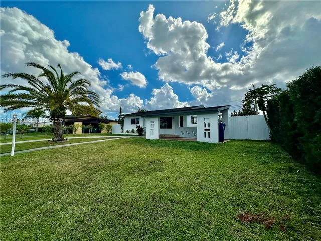a view of a house with a big yard plants and large trees