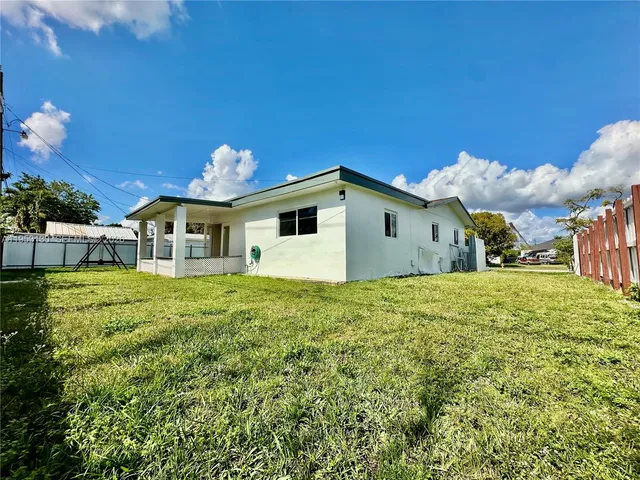 a view of a house with a yard and a large tree