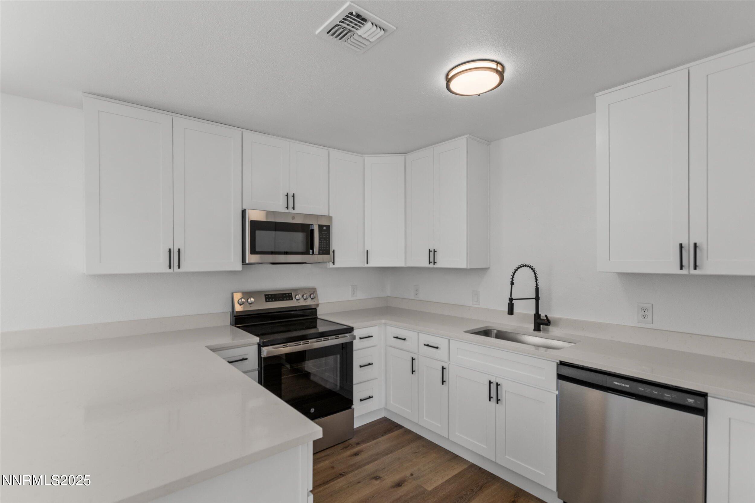 15205 North Red Rock Road Reno, NV 89508 - Photo 6 of 23 a kitchen with stainless steel appliances granite countertop a sink dishwasher a stove and a microwave oven with cabinets